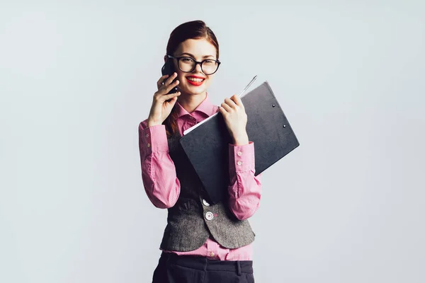 Jente med briller og røde leppestift smiler og holder en mappe i hendene – stockfoto