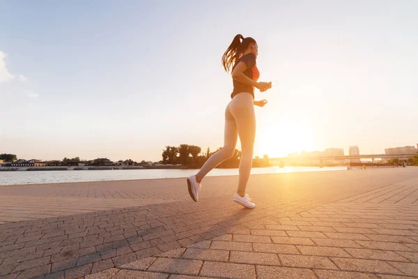 Kız Arnavut kaldırımlı sokakta günbatımında çalışır.