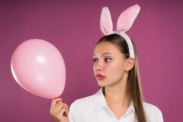 这个女孩有挡板的兔子耳朵形式和她抱着一个粉红色的气球 — 图库照片