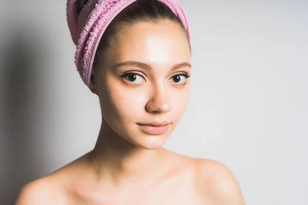 Menina bonita com uma toalha na cabeça está de pé junto à parede branca — Fotografia de Stock
