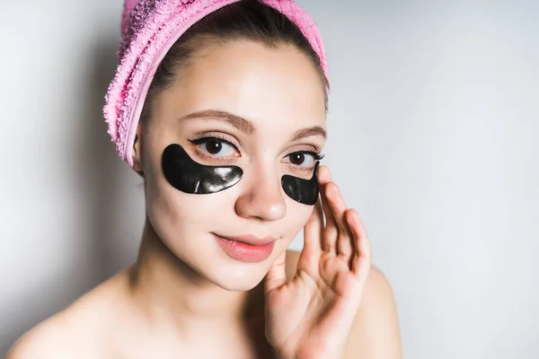 Meisje met een handdoek op haar kop zet op haar gezicht een zwart masker — Stockfoto