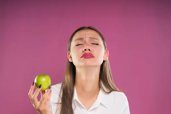 Chica arrepentida sosteniendo una manzana con los ojos cerrados — Foto de Stock