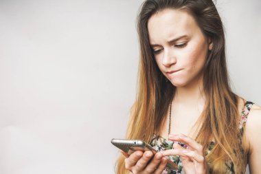 Düşünceli kızgın el smartphone ile yüz genç kız üzgün