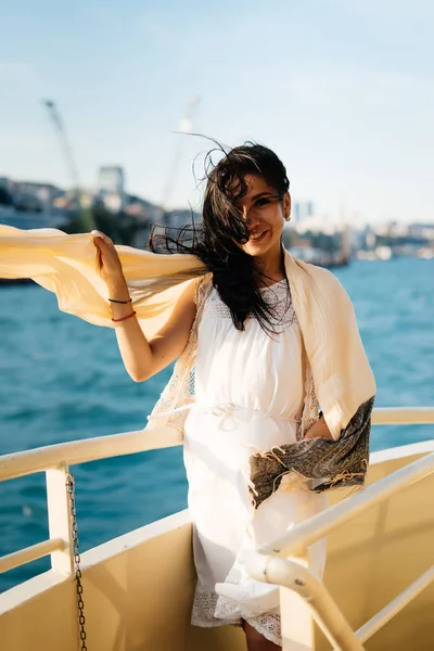 Glada leende flicka på en båt som du njuter av solnedgången, solen, insvept i en halsduk — Stockfoto