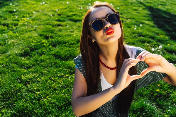 Улыбающаяся девушка в очках показывает форму сердца, летнюю любовь — стоковое фото