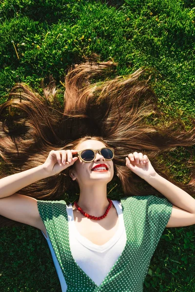 Módní vintage styl dívka v tmavých brýlích, ležící na trávě, zdraví šťastný úsměv — Stock fotografie