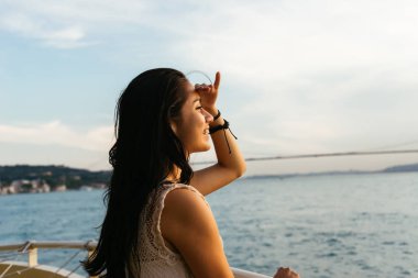 Bir kız günbatımında denizde, mesafe, Boğaz'ın bir köprüden bir şey arıyor görünüyor