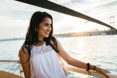 Modern bir köprü ve gülüyor, bir feribot tekne gezisi altında günbatımı yüzer adlı yatında bir güzel latin kız portresi