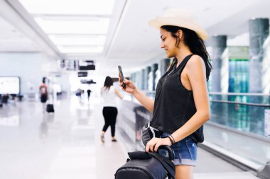 Havaalanında Smartphone kullanan kadın seyahat. Cep telefonu uygulaması ile yatılı zaman kontrol genç Doğu yolcusu