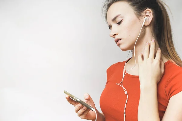 Dospívající hledá něco v telefonu, krásná smutná dívka poslechu hudby ve sluchátkách — Stock fotografie
