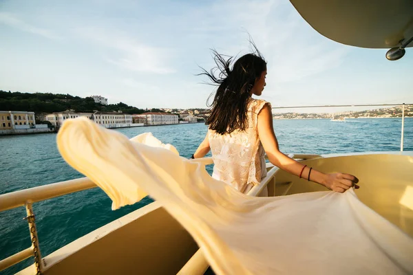 Okända flickan står på kanten av båten vid solnedgången, vyn från baksidan — Stockfoto