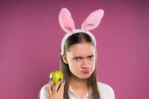 Uma menina com um rosto ofendido segura uma maçã na mão — Fotografia de Stock