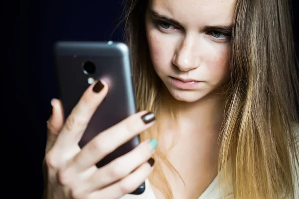 Ragazza arrabbiata con i capelli lunghi guardando nel telefono — Foto Stock