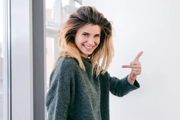 Vastag haj lány mosolyog, és azt mutatja, illetlen jel ujjaival — Stock Fotó