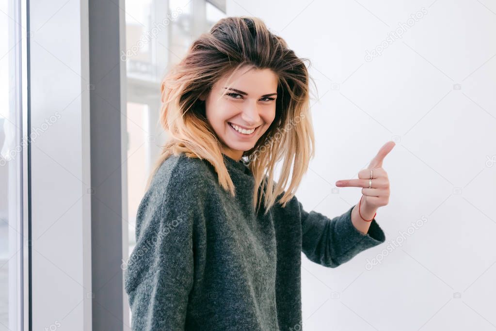 girl with thick hair smiles and shows indecent sign with fingers