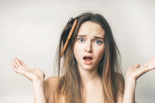 Um pente de madeira está preso no cabelo da menina e ela não sabe o que fazer . — Fotografia de Stock