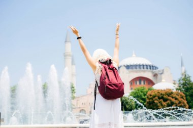 Bir eşarp ile cami ve Çeşme bir arka plan üzerine bir sırt çantası içinde tanınmayan bir kadın. Yaz tatili, gezgin