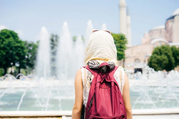 Back of a young girl in a scarf with a backpack in the background of the mosque. Summer vacation, traveler — Stock Photo, Image