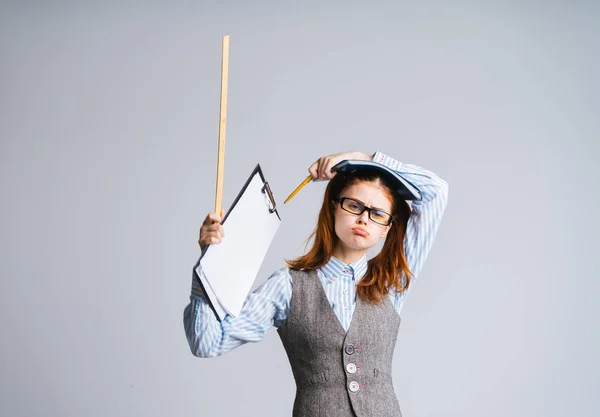 Das Mädchen hält ein Buch, einen Zeiger und eine Mappe mit Papieren in der Hand und sieht müde und wütend aus — Stockfoto