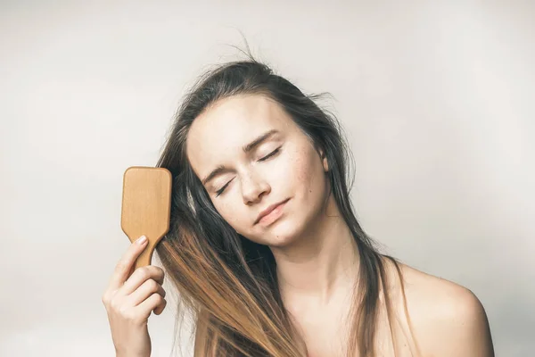 Menina com olhos fechados penteando seu cabelo — Fotografia de Stock