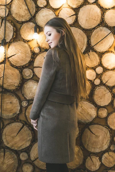 Hermosa joven en una larga blusa de pie junto a una pared inusual — Foto de Stock