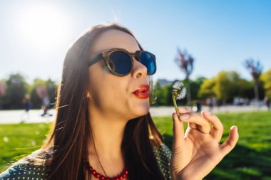 Mutlu gülümseyen komik surat kız darbe karahindiba, yaz güneş gözlüğü, günbatımı