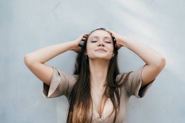 Kız gülümsüyor ve gri duvar arka planı mutlu görünüyor