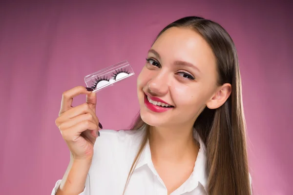 Jeune fille tient dans les mains les faux cils emballés et sourit — Photo