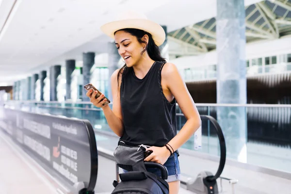 Smartphone vasıl Havaalanı olan kadın. Genç yolcusu terminalstation cep telefonu uygulaması ile yatılı zaman kontrol. Turizm tatil.