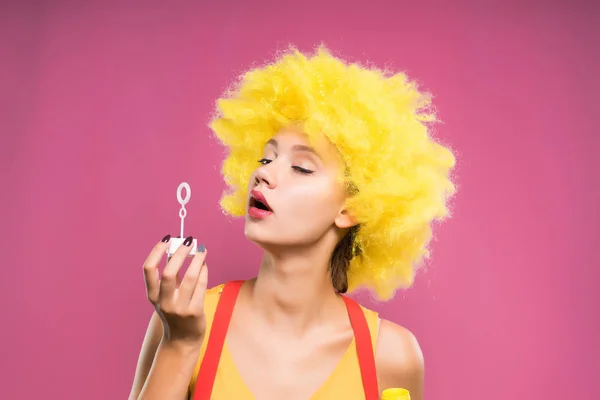 Mladá dívka v žluté paruce vyfukuje bubliny — Stock fotografie