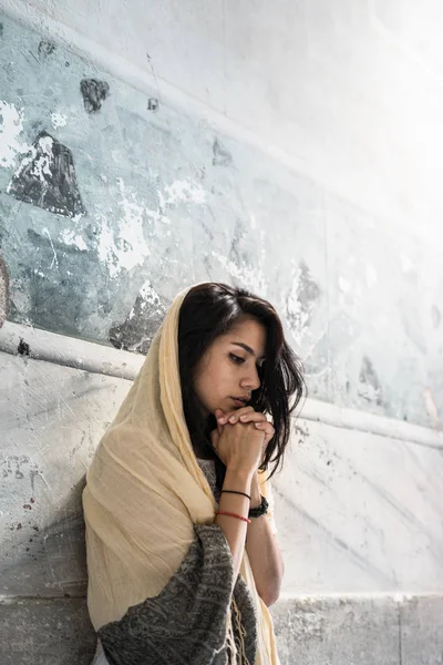 The girl prays with palms together in the rays of light, standing in the temple — Stock Photo, Image