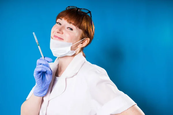Donna in abito medico e maschera che tiene una siringa in mano e sorride — Foto Stock