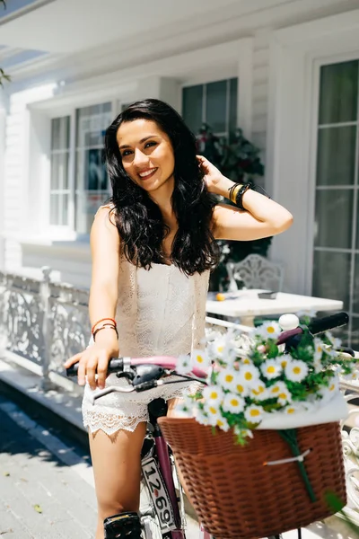 Parlayan Doğu kız gülümseyerek mutlu, Bisiklet ve siyah saçları dokunur