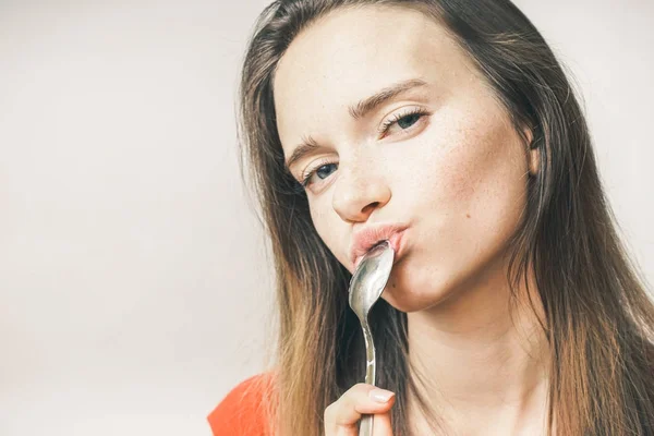 Uma menina segura uma colher perto de sua boca — Fotografia de Stock