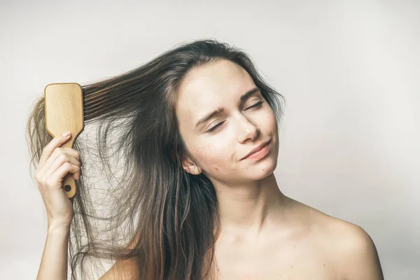 A menina tenta pentear seu cabelo longo — Fotografia de Stock