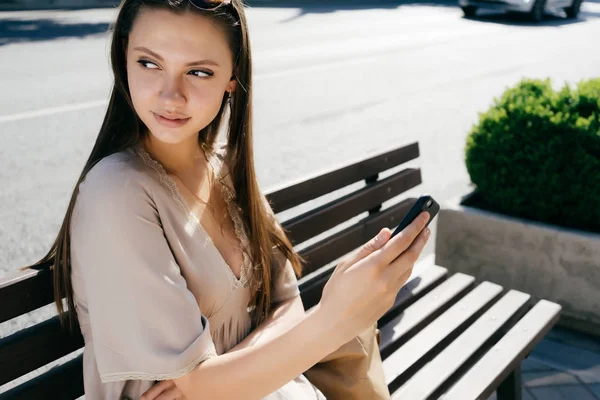 Kız bir bankta telefonuyla ilgili gizemli bir şekilde görünüyor bir kenara oturur