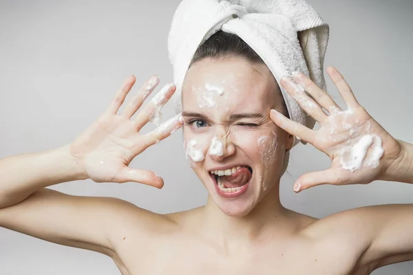 Śmieszne Kobieta w ręcznik na głowie szczęśliwy oczyszcza skórę z pianki na białym tle na białym tle. Koncepcja oczyszczający Pielęgnacja skóry — Zdjęcie stockowe