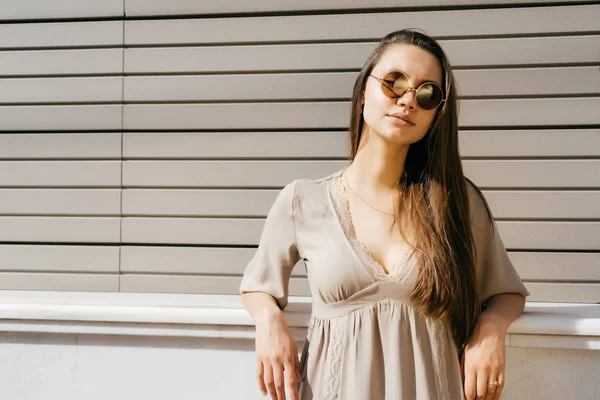 Chica posando contra la pared bajo los rayos del sol — Foto de Stock