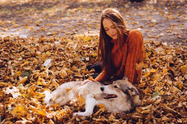 Bir kız bir sonbahar parkında köpeğiyle aittir.