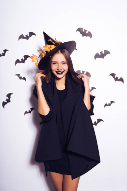 Beyaz bir arka plan üzerinde cadı elbiseli gülümseyen kız