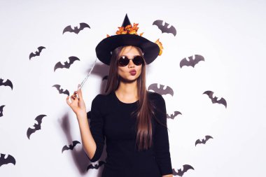 Beyaz bir arka plan üzerinde siyah gözlüklü cadı elbiseli kız