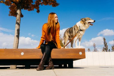 Kız köpeğiyle bankta oturuyor