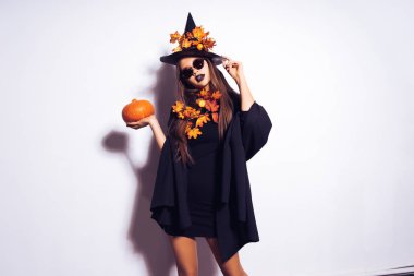 bir kız bir cadının elbiseli küçük bir kabak tutar