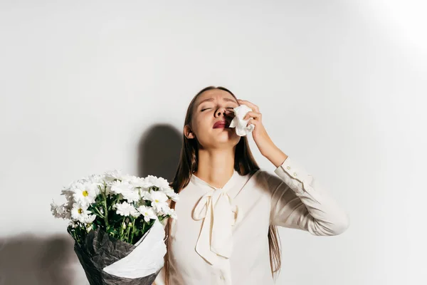 Chica molesta en una camisa blanca sostiene un ramo de flores en sus manos — Foto de Stock