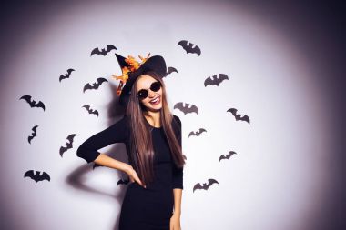 Geniş Cadılar Bayramı partisi sanat tasarımında Halloween cadı bir siyah korkunç şapka gülümsüyor. Yarasalar birkaç arka planı.