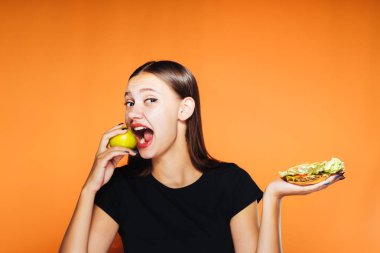 güzel bir kız bir elma ya da ağız sulandıran bir sandviç yemek iyidir seçer. Bir elma, sağlıklı gıda, lezzetli yemek ısırmak bir kız istiyor