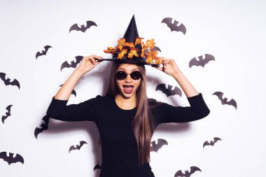 neşeli kız bir Cadılar Bayramı partisine gidiyor. Elbise, sonbahar turuncu yaprak üzerinde siyah bir şapka cadı