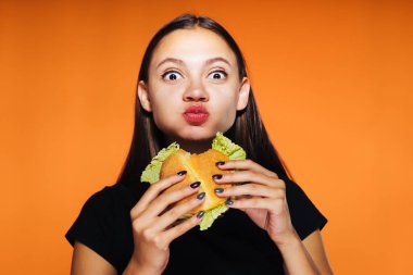 güzel aç kız iştahla ona burger kadar yiyor ve izole, kameraya, lezzetli yemekler görünüyor