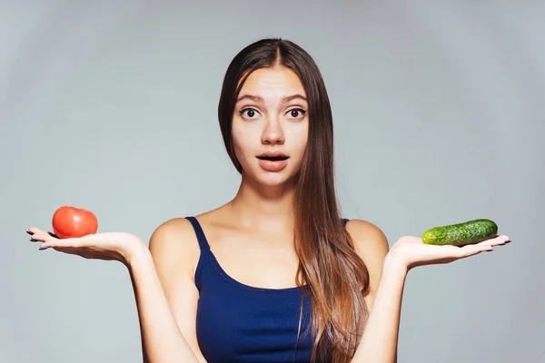 Surprise fille regarde la caméra et tient une tomate et concombre, légumes, régime alimentaire — Photo