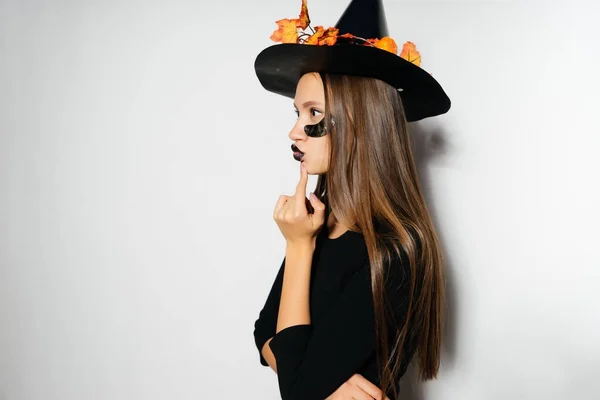 Модная Хэллоуинская ведьма в большой черной шляпе с листьями, собранными на вечеринку, осенний праздник Хэллоуина — стоковое фото